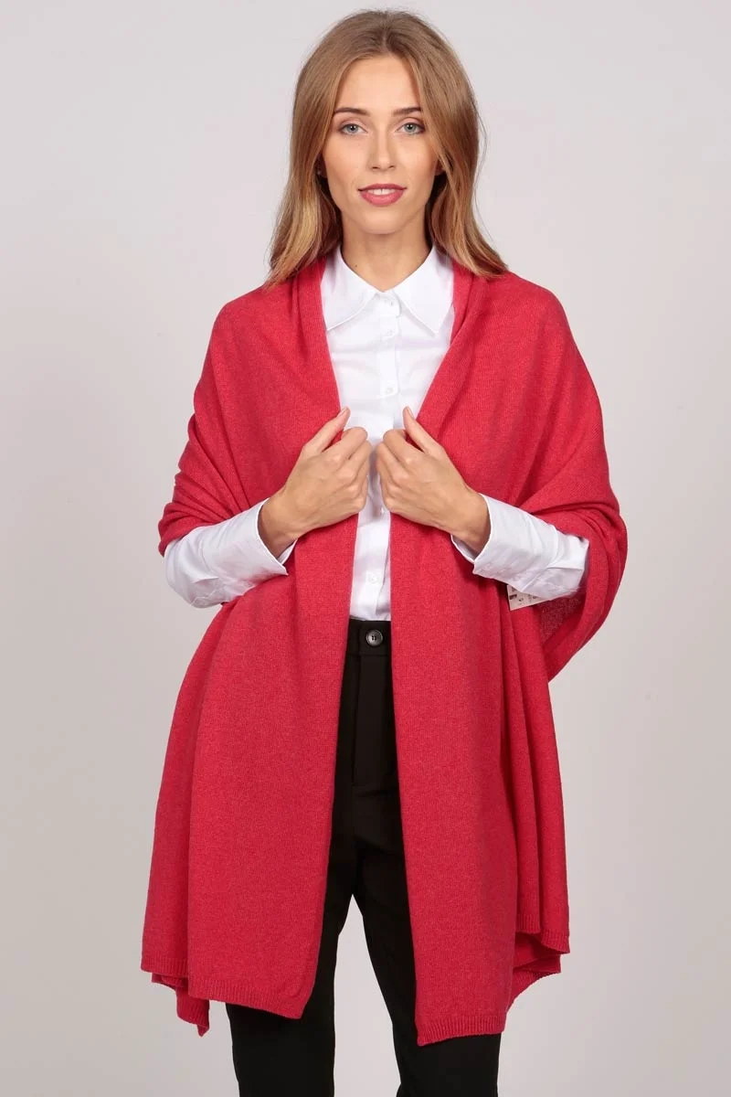 A cashmere wrap in coral red worn as a simple drape